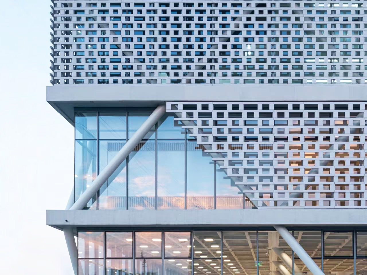 A close-up shot of the dealership's facade, featuring the pristine white LOPO ceramic bricks, highlighting the intricate perforation design and smooth texture of the building's exterior.